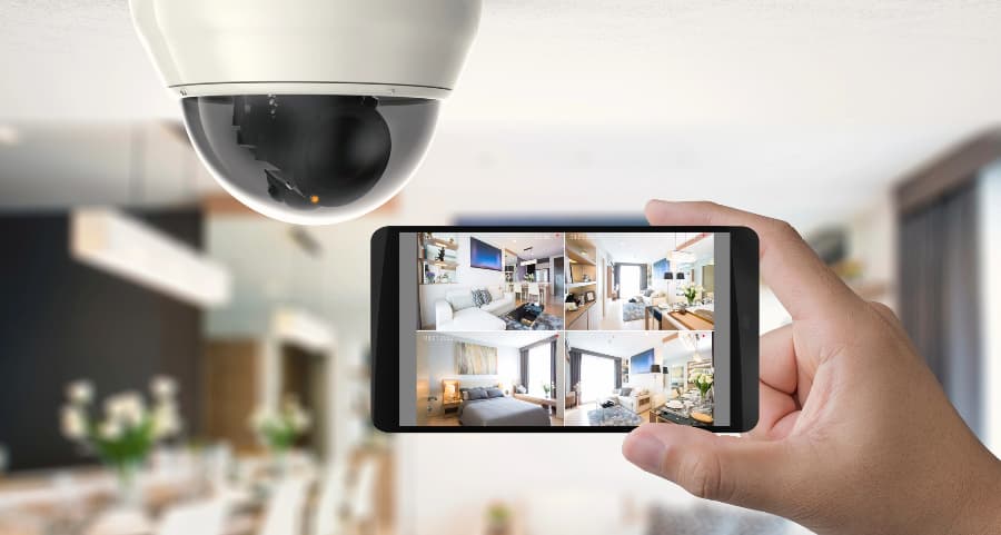 Homeowner holding smartphone with video feed from security cameras in New Brunswick