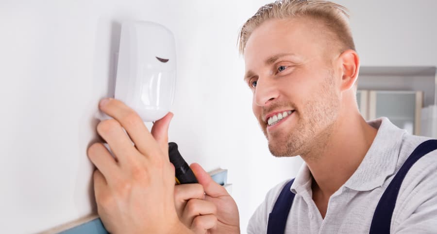 Man placing a motion sensor in a living area